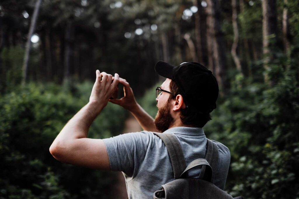 Young man taking a photograph in a nature park. © nikki_meel / Envato Elements