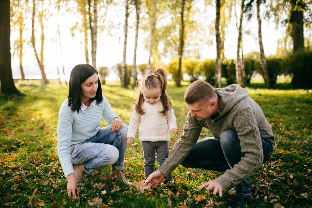 Parents and young girl experiencing nature in a local park, inspecting leaves by Yavorandriy / Envato Elements