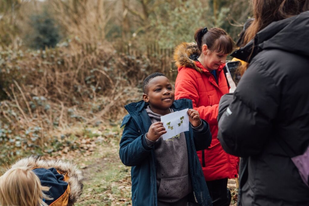 An image shows a child holding up a piece of wild artwork he has made