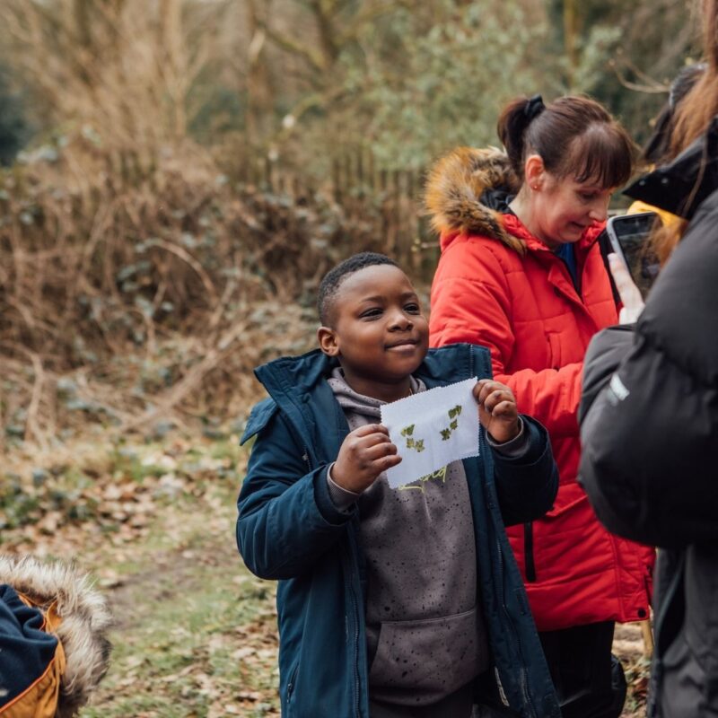 An image shows a child holding up a piece of wild artwork he has made